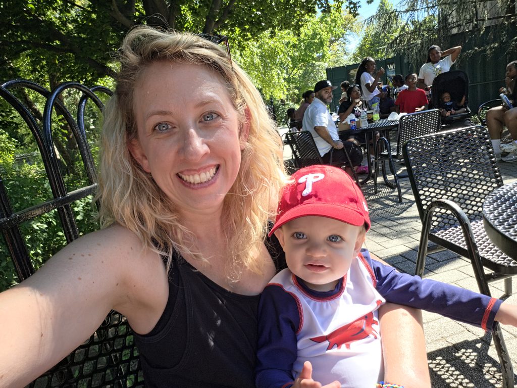 Victoria Prisco smiling for a selfie with her young son during an outdoor baseball game.